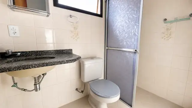 Banheiro da suíte com box de vidro e bancada em granito