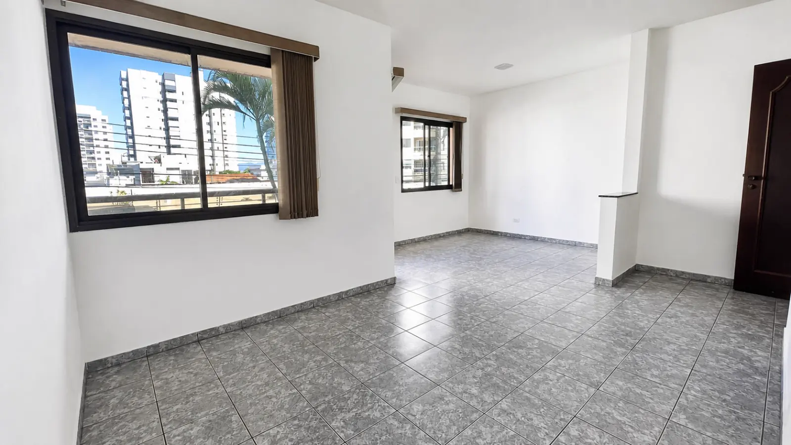 Sala ampla do apartamento com duas janelas e luz natural