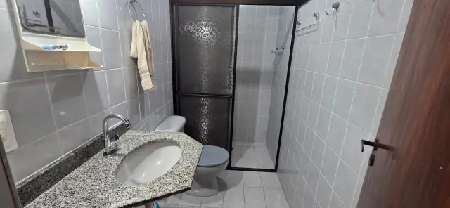 Banheiro social com pia em granito, espelho e box com divisor