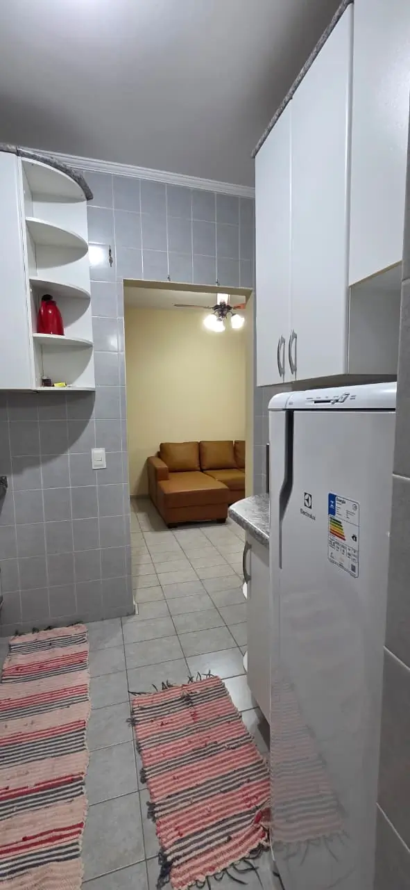Cozinha com armários, geladeira e passagem para a sala