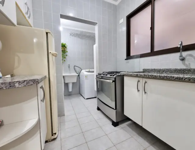 Cozinha com geladeira, cooktop e lavanderia com tanque ao fundo