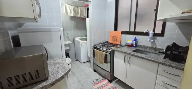Cozinha com cooktop, armários e área de serviço com máquina de lavar