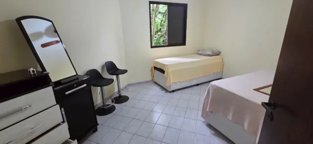 Quarto com duas camas de solteiro, cômoda com espelho e janela com vista para o verde