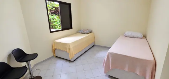 Quarto com duas camas, banquetas e janela com vista para a vegetação
