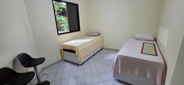 Dormitório com duas camas de solteiro e janela voltada para o verde