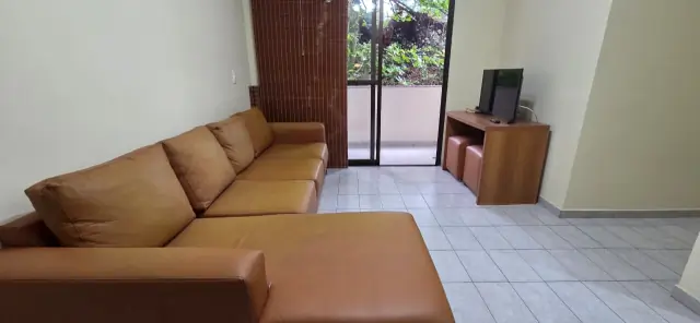 Sala com TV e porta de vidro que dá acesso à varanda