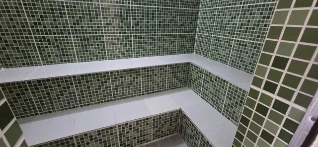 Sauna do condomínio com revestimento em mosaico verde