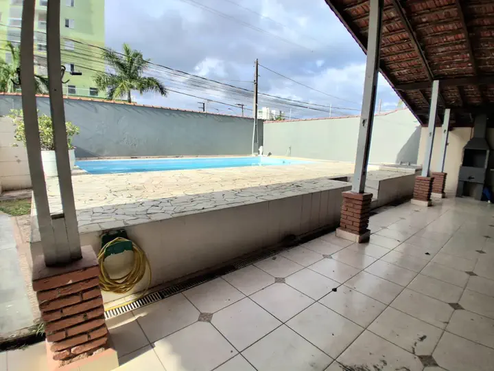 Espaço gourmet coberto com churrasqueira em alvenaria e bancada com pia integrada à piscina
