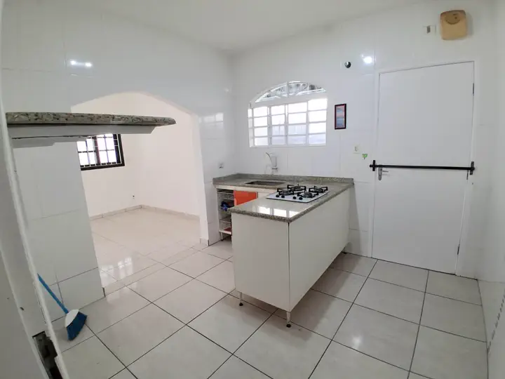 Cozinha azulejada até o teto com balcão de granito e vista para a sala