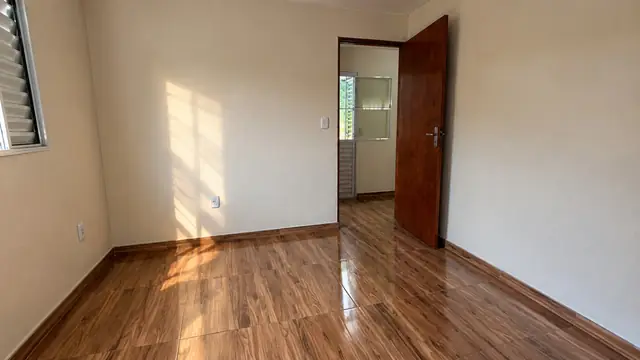 Ambiente interno amplo com piso claro e porta de madeira