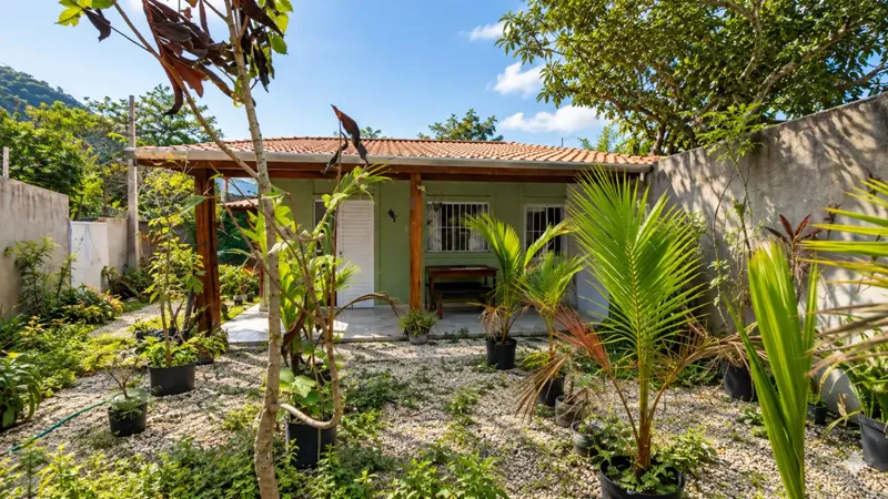Fachada da casa térrea com varanda coberta em madeira, no Massaguaçu