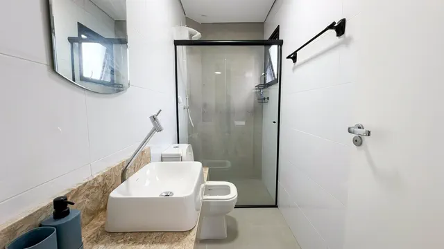 Banheiro com box de vidro e revestimento azul
