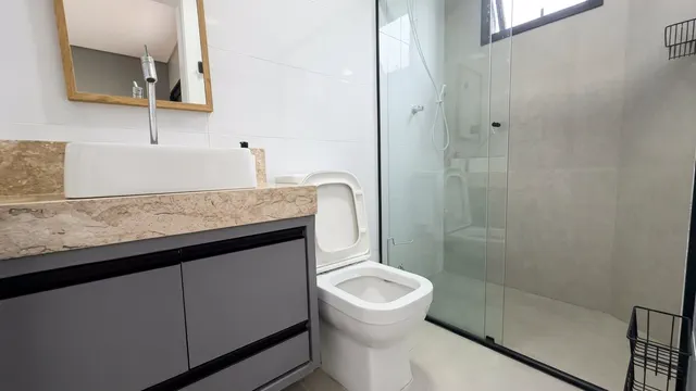 Banheiro com espelho, bancada e box de vidro