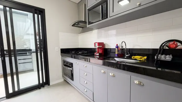 Cozinha com bancada escura e porta de vidro para a área externa
