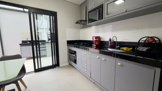 Cozinha integrada com mesa de refeições, armários e geladeira