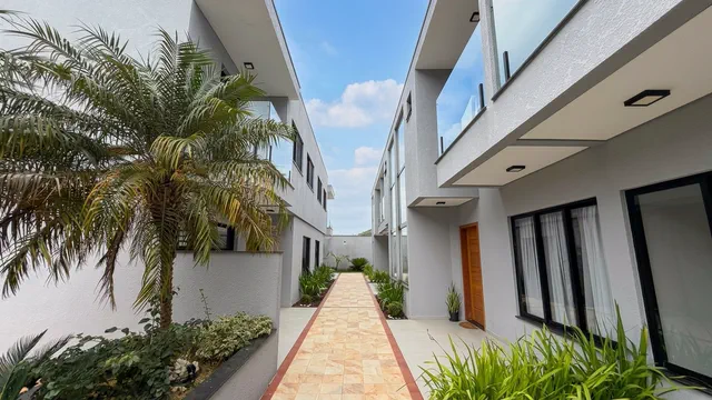 Fachada do sobrado no Condomínio Talismã, com jardim tropical e palmeira