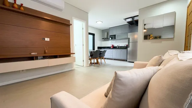Living com sofá, painel ripado e cozinha integrada