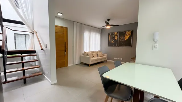 Sala de estar integrada com escada de madeira e mesa de refeições