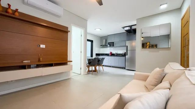 Sala ampla com sofá em L e cozinha integrada ao fundo